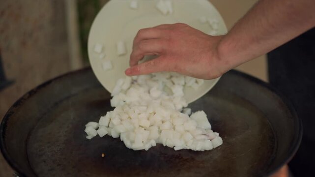 Chef adding diced cuttlefish to a paella pan
