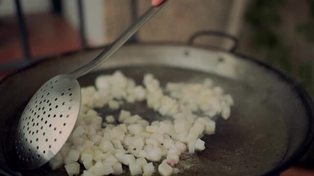Chef stirring diced cuttlefish in a paella pan