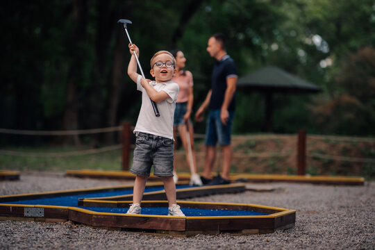 Young boy playing mini golf enjoying family fun