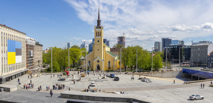 Tallinn, Estonia - 16 May 2026: View of Freedom Square with St. John's Church, people walking across the paved plaza, and modern city skyline under a clear blue sky.