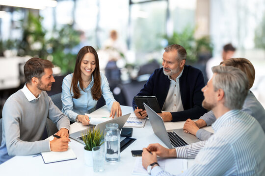 Successful businesspeople working in a coworking space working with laptop discussing strategy and business plan in modern office.