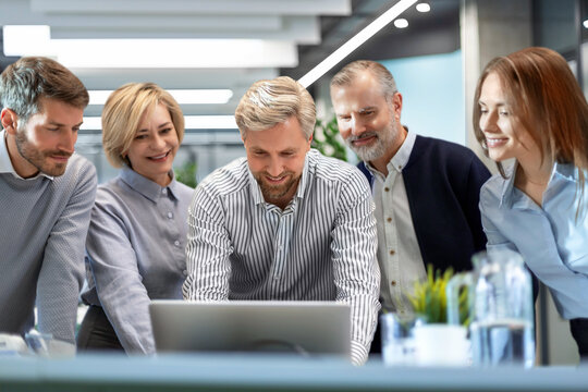 Business people discussing work together using a tablet and laptop taking notes in a modern office