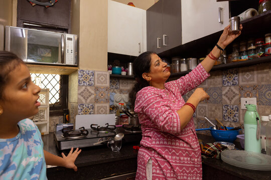 Woman reaching for a container on a high kitchen shelf