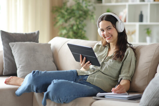 Happy student wearing headphone studying online looking at you