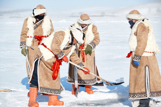 People ice-fishing on the frozen lake during the cold winter.