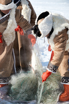 People ice-fishing on the frozen lake during the cold winter.