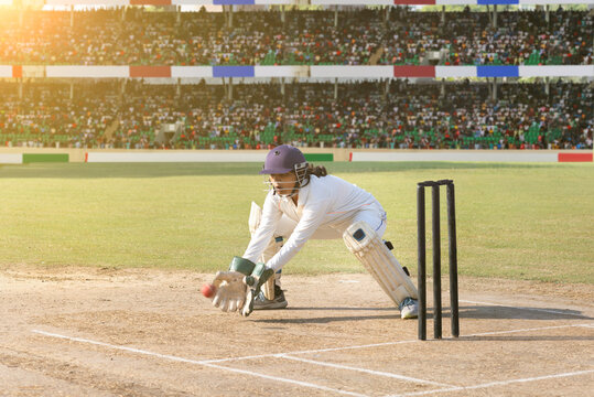 Wicketkeeper diving to catch the ball in a cricket match