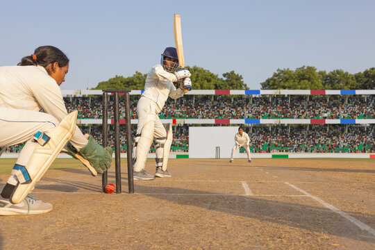 Batsman playing a defensive shot in a cricket match