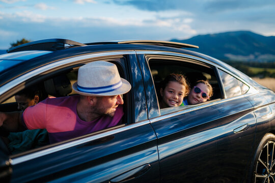 Happy family enjoying drive in their new electric car.