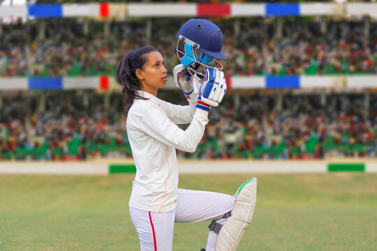 Female cricketer inspecting her helmet on the field