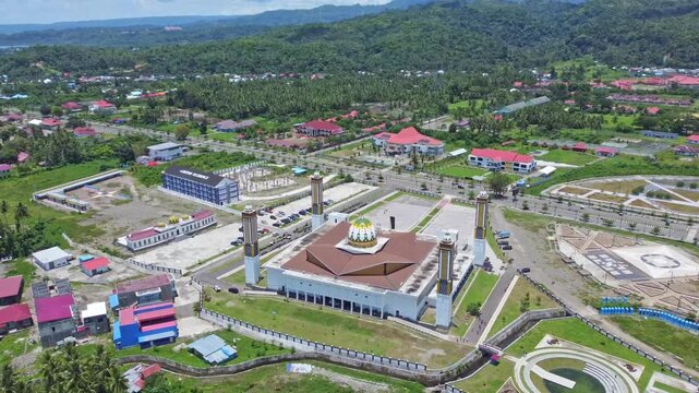 An aerial shot of a magnificent mosque Masjid Raya Shaful Khairaat Sofifi Tidore with mountains and the sea. Ideal for projects on religion, travel, and culture