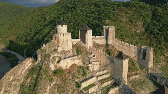 Aerial view of Golubac medieval fortress on cliff above Danube river at sunset, historic landmark in Serbia, 4k