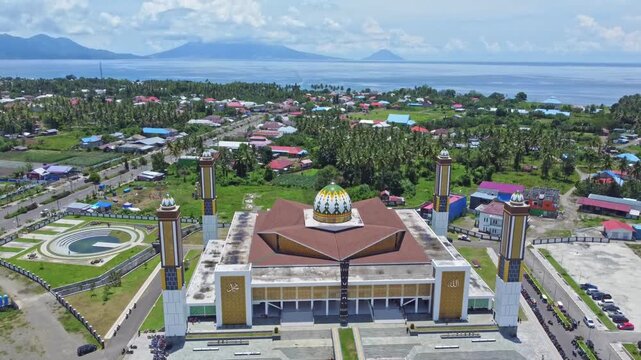 An aerial shot of a magnificent mosque Masjid Raya Shaful Khairaat Sofifi Tidore with mountains and the sea. Ideal for projects on religion, travel, and culture