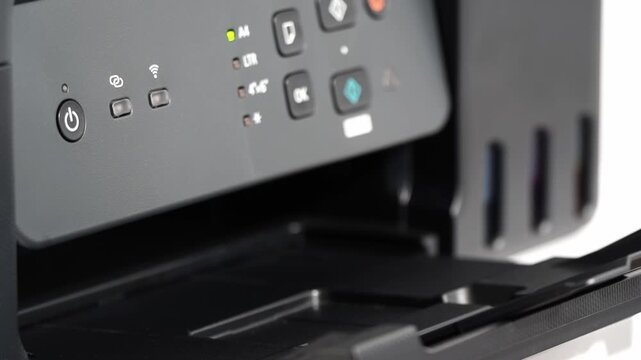 Black printer with control panel and open tray. Buttons and lights indicate active functions. Modern device ready for printing tasks. Ideal for tech or office scene backgrounds