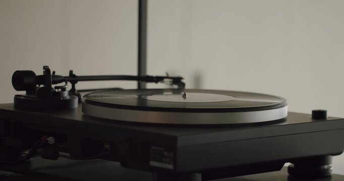 Close up view of a vinyl record spinning on a classic turntable. The stylus on the tonearm is carefully placed on the LP, bringing nostalgic melodies to life in a warm, inviting room