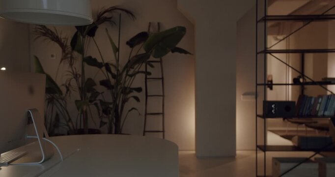 Cozy contemporary home office interior with a computer on a desk and warm ambient lighting. Elegant and functional workspace design for remote work, study, or creative projects at night