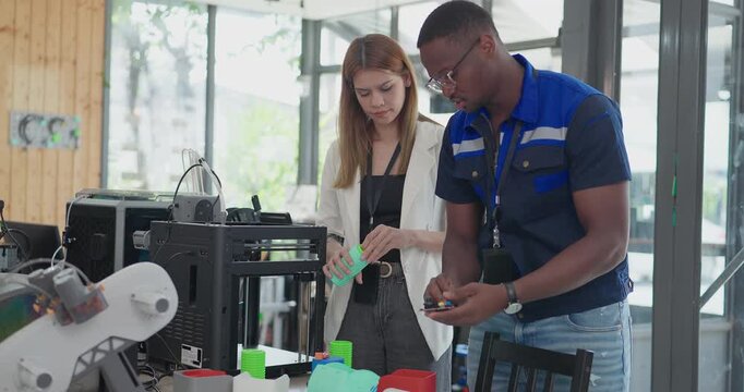 Engineers examining 3D printed prototype from recycled material at desktop printer in eco workshop