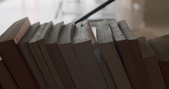 Row of old books falling one by one in a classic domino effect, a powerful visual metaphor for chain reactions, consequences, and the unstoppable spread of knowledge or ideas in slow motion