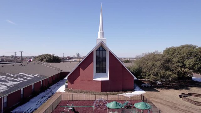 4K drone pullback footage of a Baptist church in Midlothian, Texas, featuring stained glass windows and a prominent white steeple, showcasing community architecture and faith-based landmark.