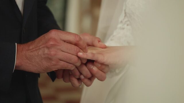 Groom placing wedding ring on bride&rsquo;s finger during ceremony. Intimate close-up capturing love, commitment and the symbolic moment of marriage vows.