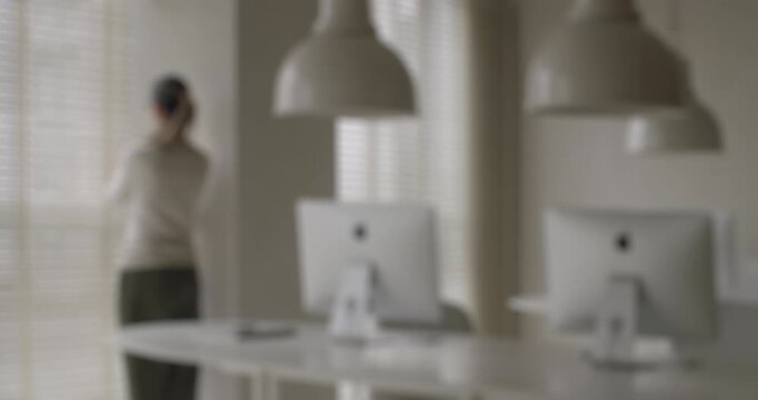 Out of focus businesswoman celebrating success, jumping and dancing in an empty modern office after working on computers, concept of joy, happiness, achievement, and a fresh start