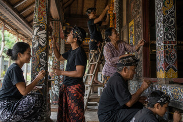 Obraz premium Artisans paint intricate patterns on traditional wooden pillars