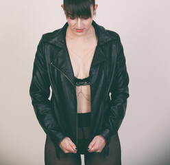 Obraz premium Frau mit Lederjacke und schwarzem Outfit im Studio. Ausdrucksstarkes Fashion-Motiv für Selbstbewusstsein, Urban Style, Rock Chic, Mode und moderne Weiblichkeit.