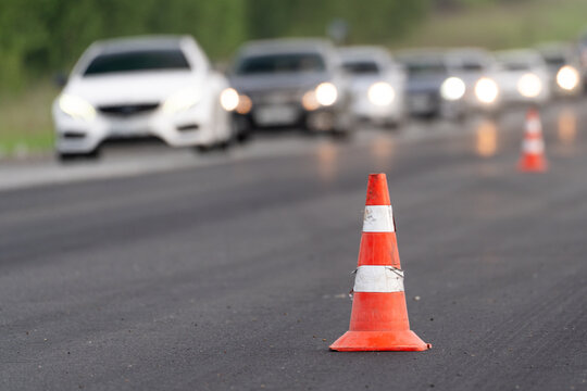 Traffic cones on road with blurred cars and headlights, road work, lane closure, traffic restriction, traffic delay and driver warning