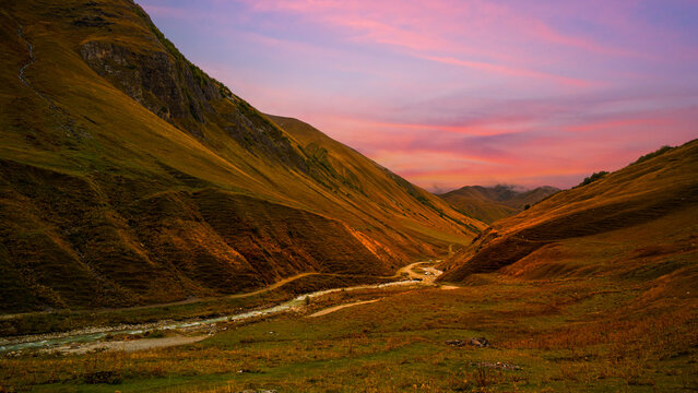 Scenic mountain valley with winding river under a colorful sunset sky