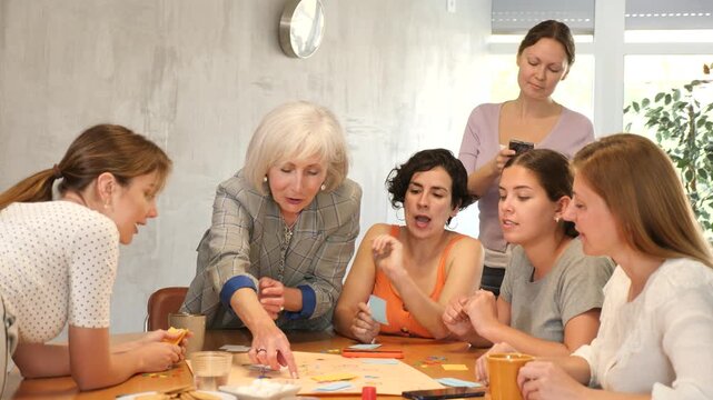 Women spend time over cup of coffee and playing popular board game.Senior female moderator throws stones and determines order of parties