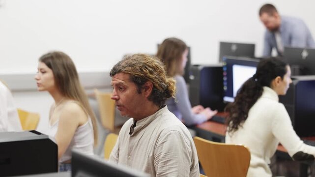 Side view on concentrated male student sitting at library desk with pc, preparing for exam in computer class. High quality 4k footage
