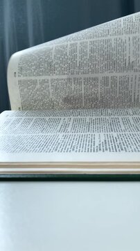 Vertical video. The woman flips through the pages. A large encyclopedia in a green cover, information search. The student searches, reads and learns new data