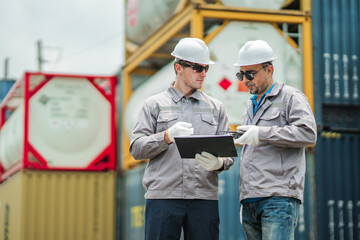 Logistics supervisors review shipment documentation and cargo verification records at container terminal, supporting freight transportation planning and supply chain management operations. © Wanwajee