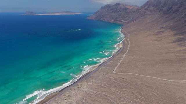 Aerial Flyover above  Famara Beach Cliffs and Coastal Village in Northwest Lanzarote