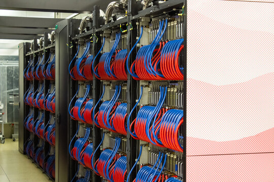 Lugano, Switzerland - 18 March 2026: View of the Swiss National Supercomputing Centre featuring rows of high-performance server racks with intricate red and blue liquid cooling cables.