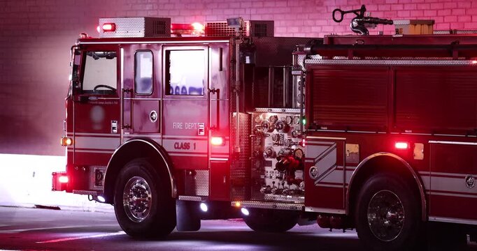 A Fire Engine with flashing red lights arrives at the scene of an emergency at night.