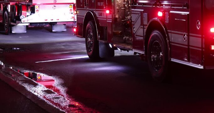 A Fire Engine with flashing red lights arrives at the scene of an emergency at night.