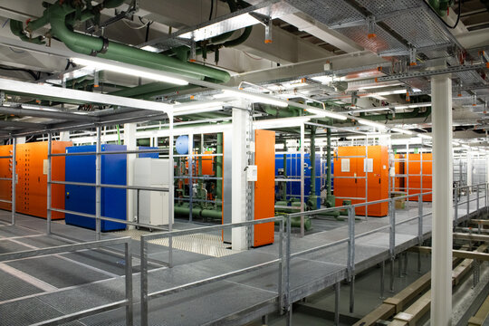 Lugano, Ticino, Switzerland - 18 March 2026: View of Swiss National Supercomputing Centre with colorful server cabinets, industrial piping, and metal walkways in a data center.