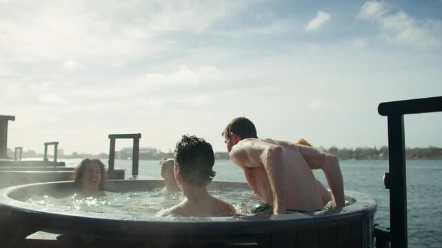 Steam rises as friends unwind in an outdoor hot tub on the waterfront deck
