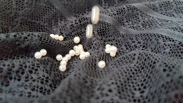 White Pearls Falling in Super Slow Motion on Black Lace Fabric