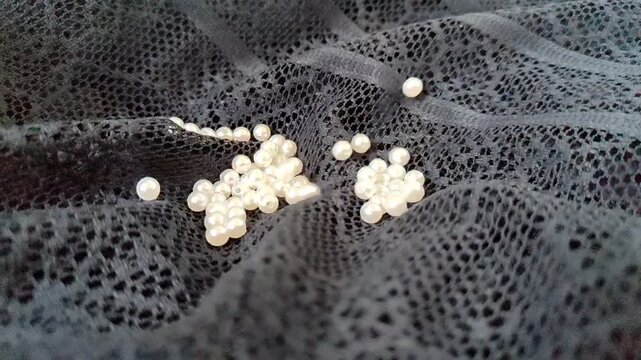 Elegant White Pearls Rolling on Black Brocade Texture in Slow Motion