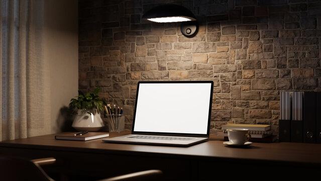 Modern workspace with white screen laptop and coffee on table beside brick wall under warm lamp light