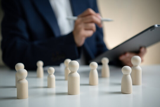 Human resources management concept with wooden figures and HR professional analyzing workforce data supporting employee assessment team planning talent strategy and organizational success