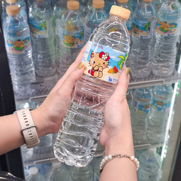 Person holding a plastic bottle of Singha mineral drinking water featuring a licensed Hello Kitty cartoon character design on May 18, 2026 in Bangkok, Thailand