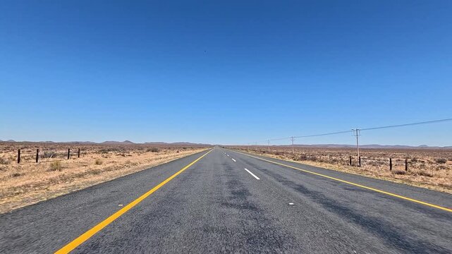 Highway through barren African desert landscape on travel journey, driving POV