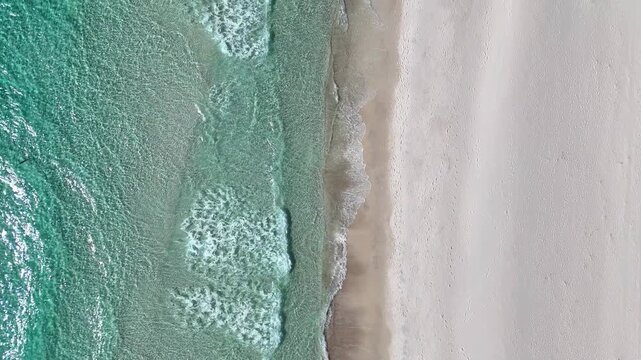 Amazing top-down aerial fly of turquoise ocean waves washing onto pristine white sandy Panama City Beach coastline, Florida, US