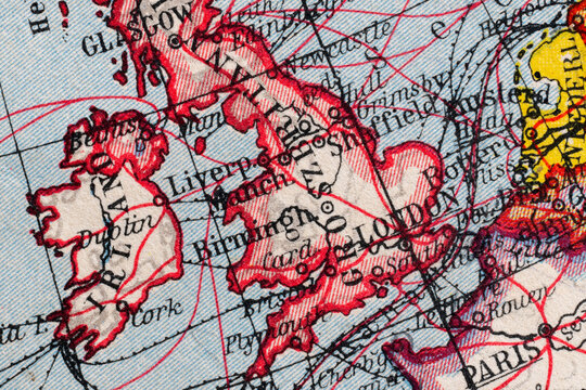 Close-up macro image of a vintage map fragment showing Ireland and Great Britain with route lines, old place names and aged paper texture. Historical cartography background for travel, geography and a