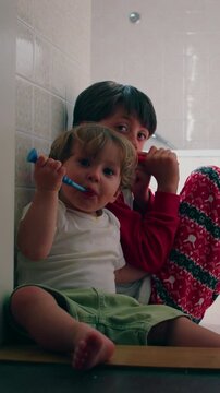 Children brushing teeth together before bedtime in family bathroom, highlighting healthy habits, sibling influence, childhood development and everyday parenting routines