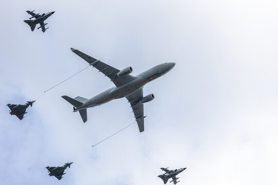 European US MRTT tanker aircraft flies formation jet fighter during aerial demonstration. Military aviation display air refueling capability operational readiness strategic support modern air power