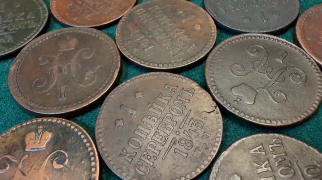 Close-up of old worn copper 1 kopeck coins 1839-1848 Russian Empire Nicholas I spread on green fabric, showing vintage money, age, texture, and collecting value.